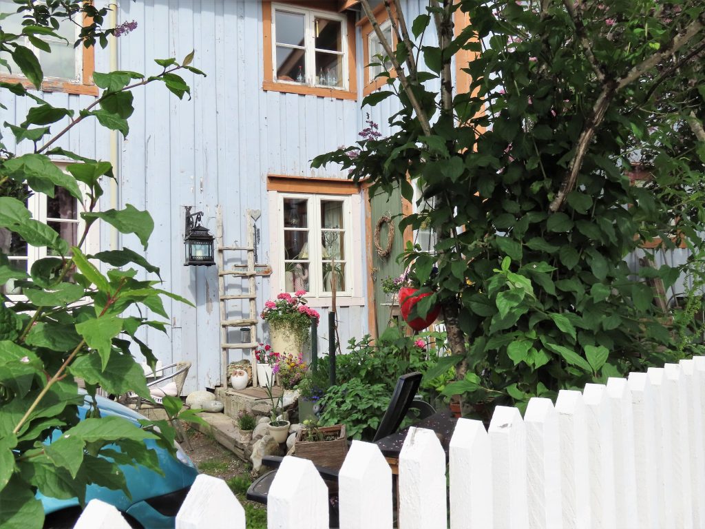 En titt over staikkgjerdet til en bolig i Sjøgata